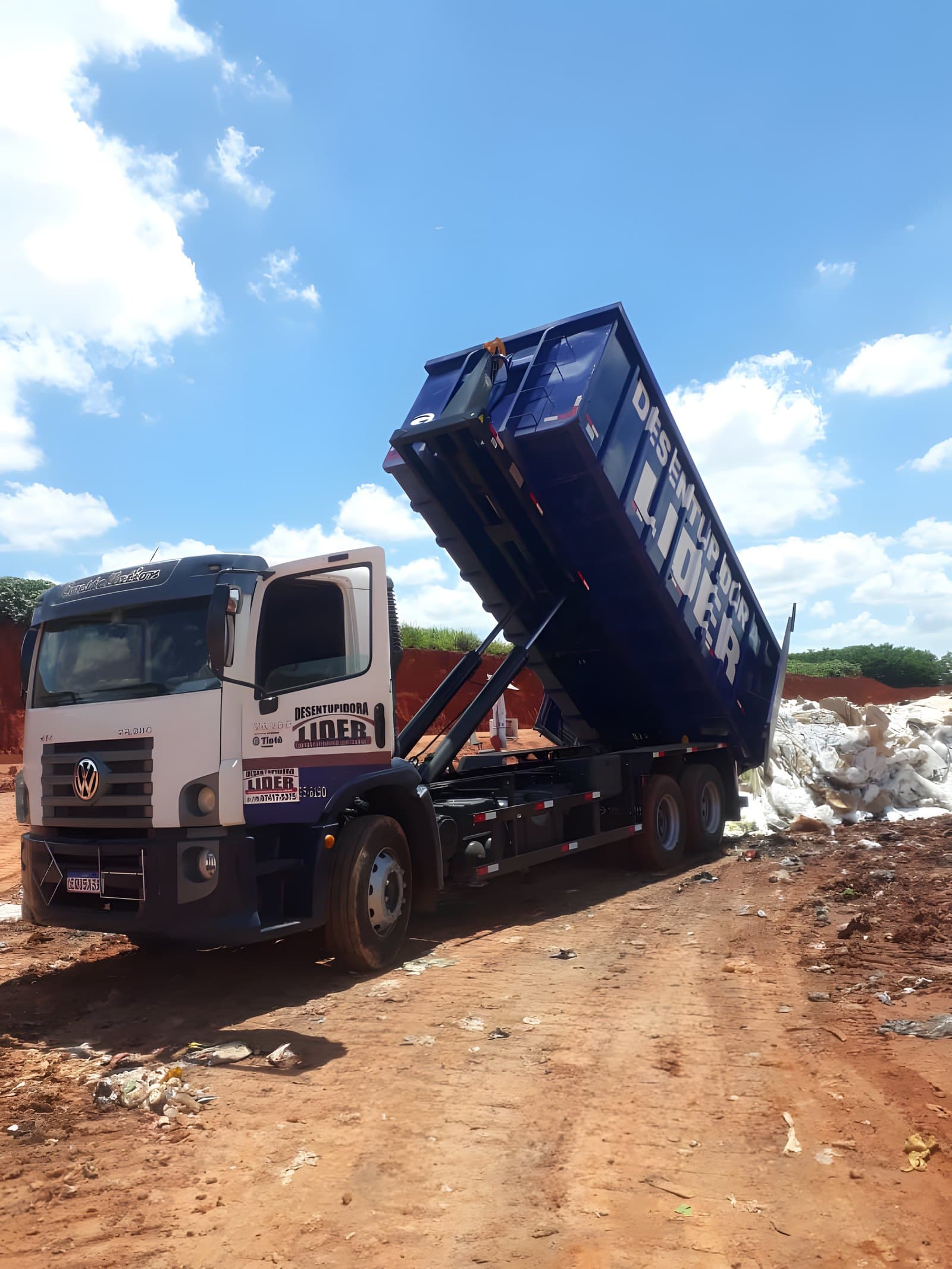 Caminhão do Grupo Líder basculando caçamba roll-on em aterro licenciado